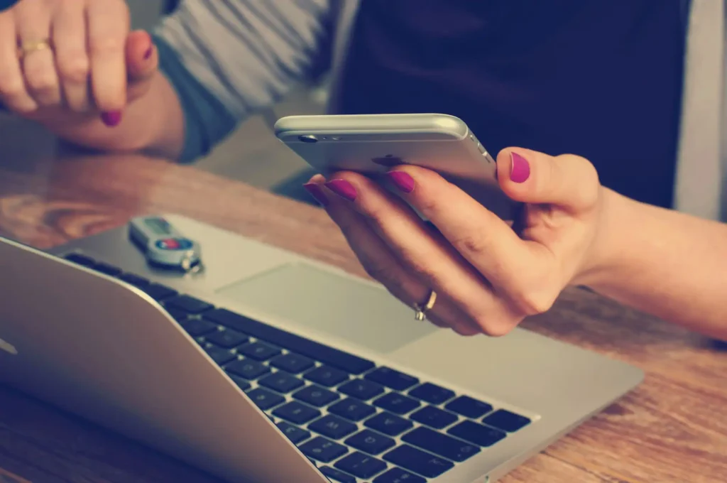 In the picture, the hands of a woman working on a laptop.