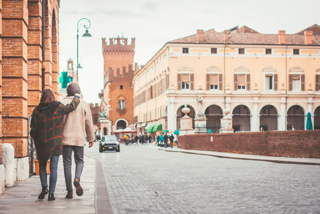 In the picture, a couple walking down a street in Ferrara city center.