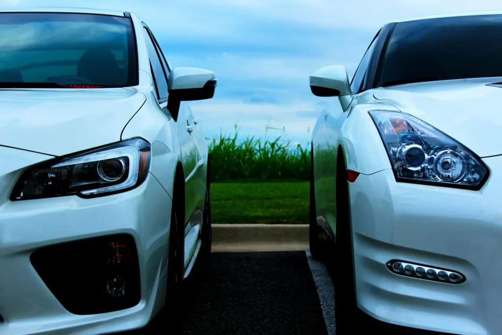 In the picture, a close-up of two white cars in a parking lot.