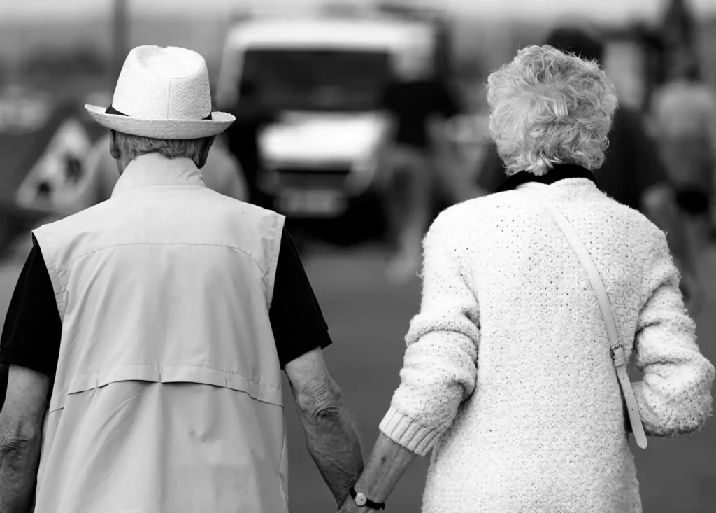 In the picture, an old couple walking while holding hands.